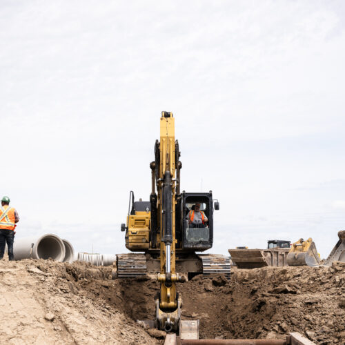 OSWCA, Employee operating excavator, employee standing to left near pipe, 24053_BUILDWITT_1744-e1731364756275