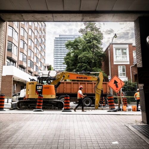 OSWCA, employee walking next to worksite, orange hard hat, from inside garage looking out to street, 24067_BUILDWITT_0259