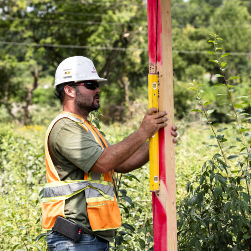 OSWCA, employee, white hard hat, orange safety vest, sunglasses, green t shirt, measuring wood, 24067_BUILDWITT_0992