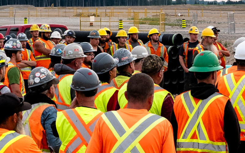 OSWCA, employees huddled for morning meeting, hard hats, safety vests, Group-43-1
